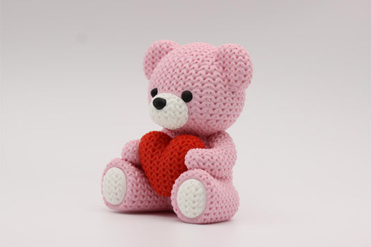 3D-printet figur av en rose teddybjørn i strikket design som holder et hjerte
