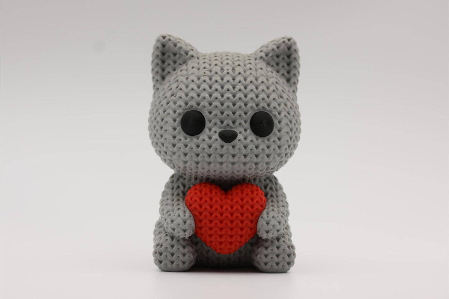 3D-printet figur av en grå katt i strikket design som holder et hjerte