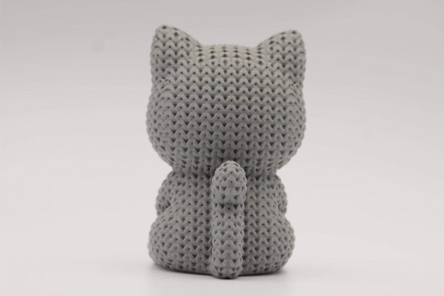 3D-printet figur av en grå katt i strikket design som holder et hjerte