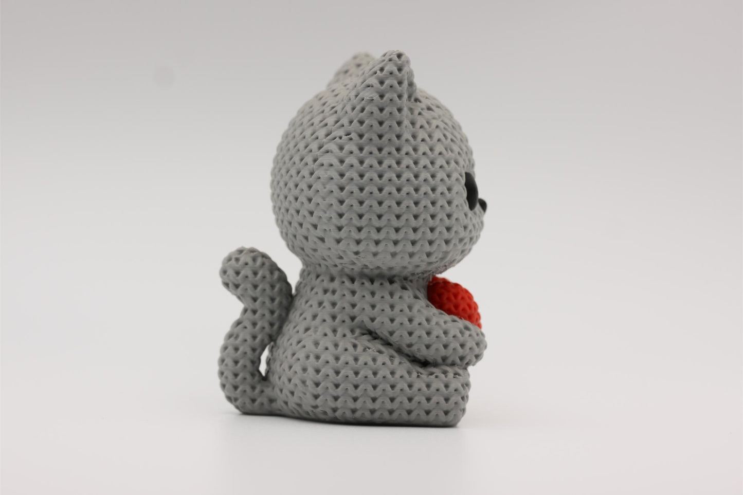 3D-printet figur av en grå katt i strikket design som holder et hjerte