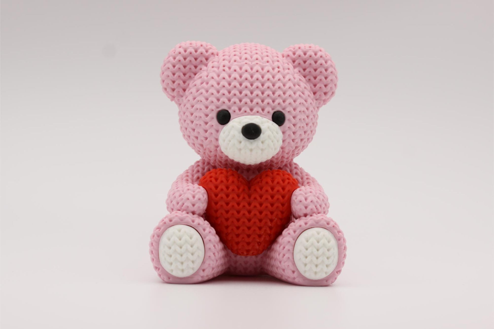 3D-printet figur av en rose teddybjørn i strikket design som holder et hjerte