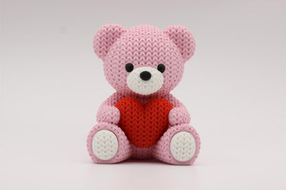 3D-printet figur av en rose teddybjørn i strikket design som holder et hjerte