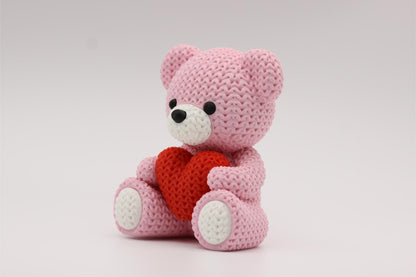 3D-printet figur av en rose teddybjørn i strikket design som holder et hjerte