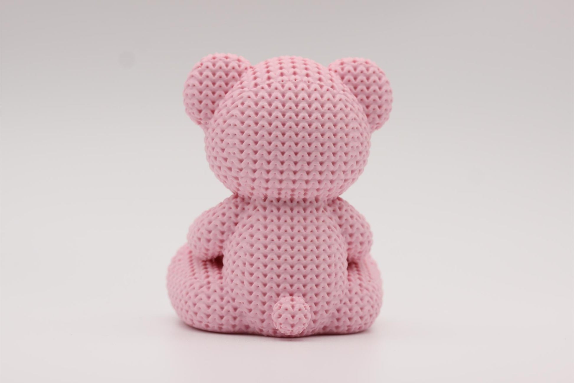 3D-printet figur av en rose teddybjørn i strikket design som holder et hjerte