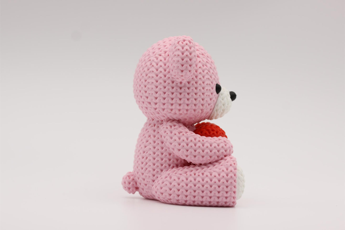 3D-printet figur av en rose teddybjørn i strikket design som holder et hjerte