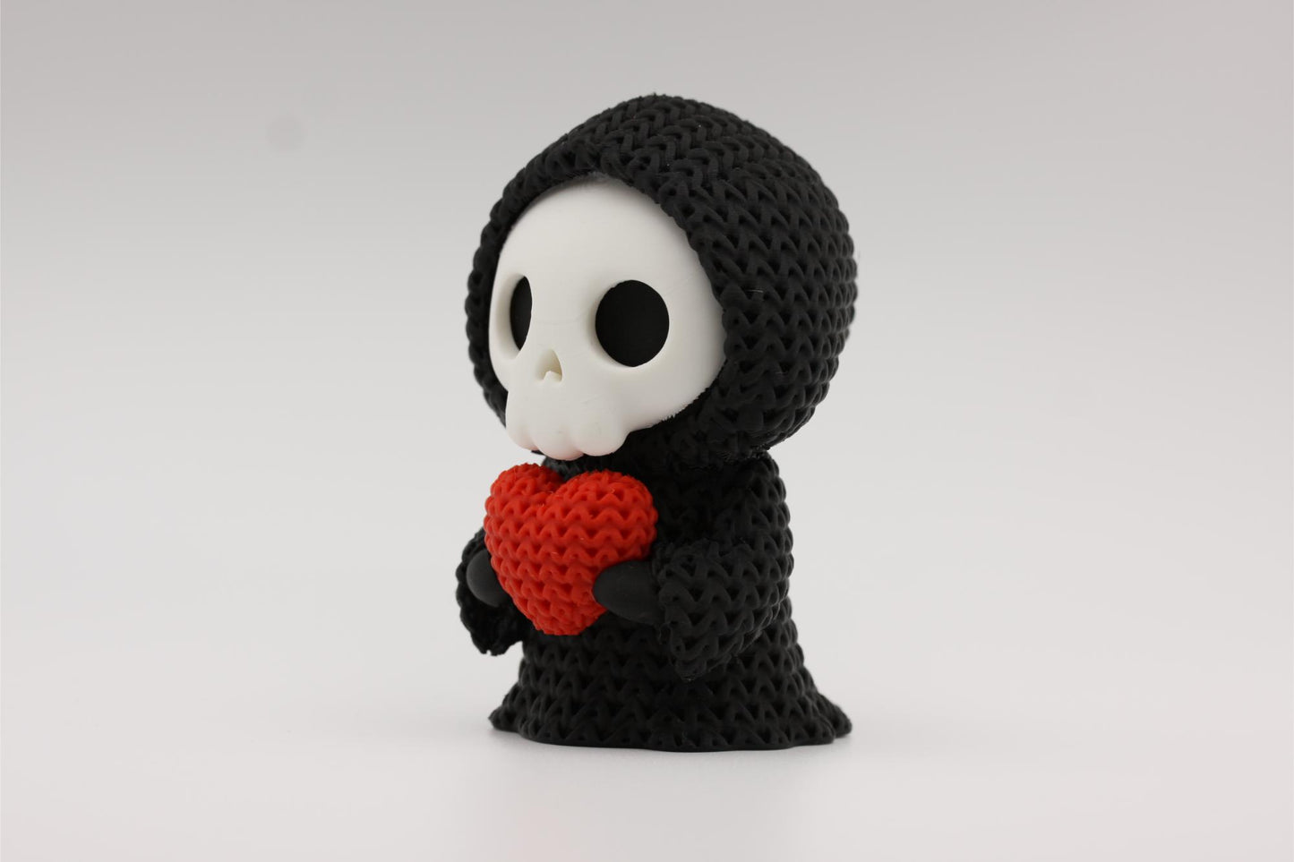 3D-printet figur av Grim reaper i strikket design som holder et hjerte