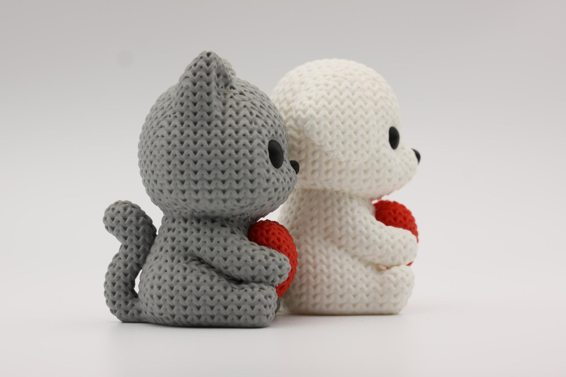 Katt og hund som holder et hjerte 3D-printet i strikket design