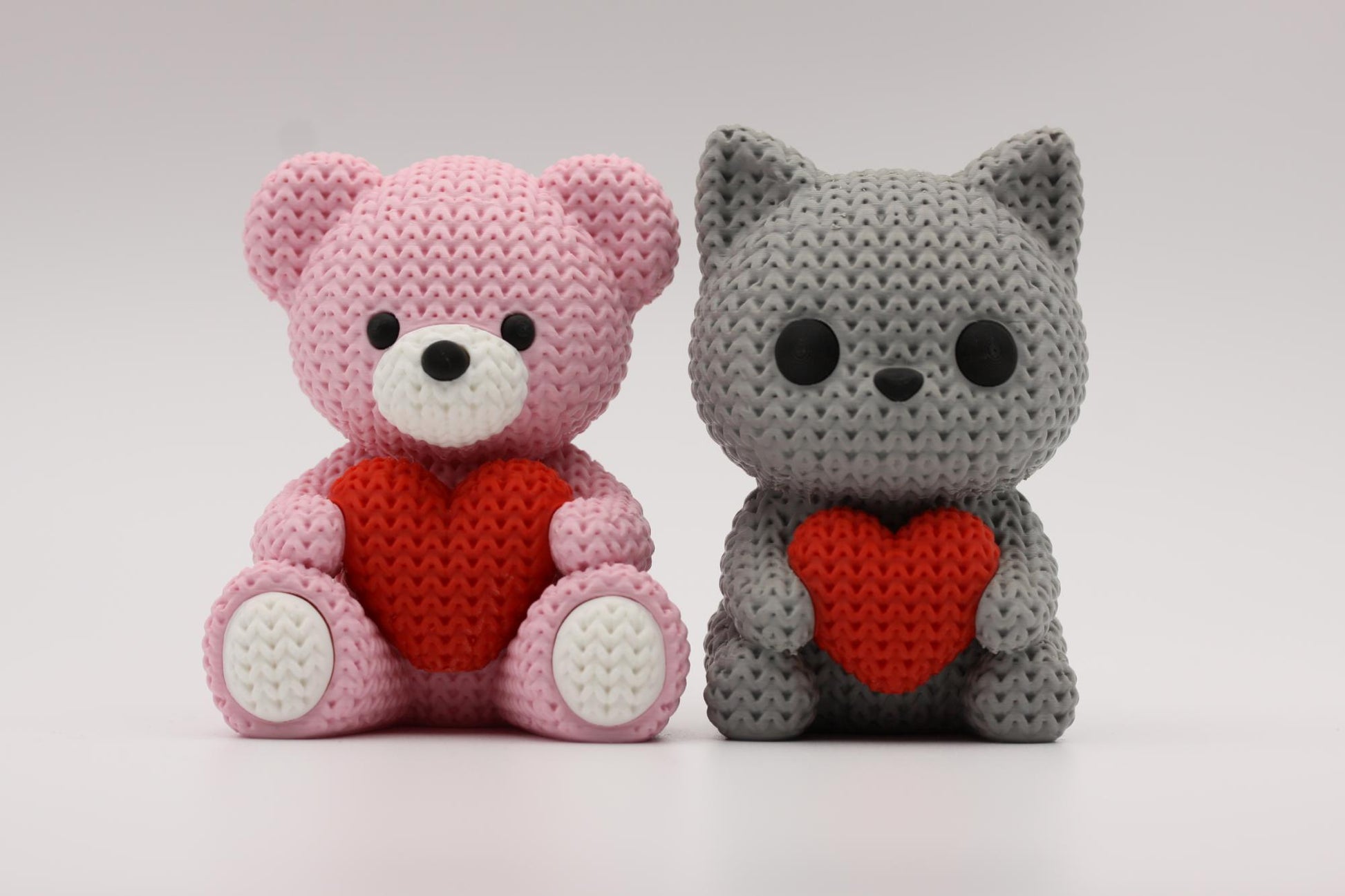 Teddybjørn og katt som holder et hjerte 3D-printet i strikket design