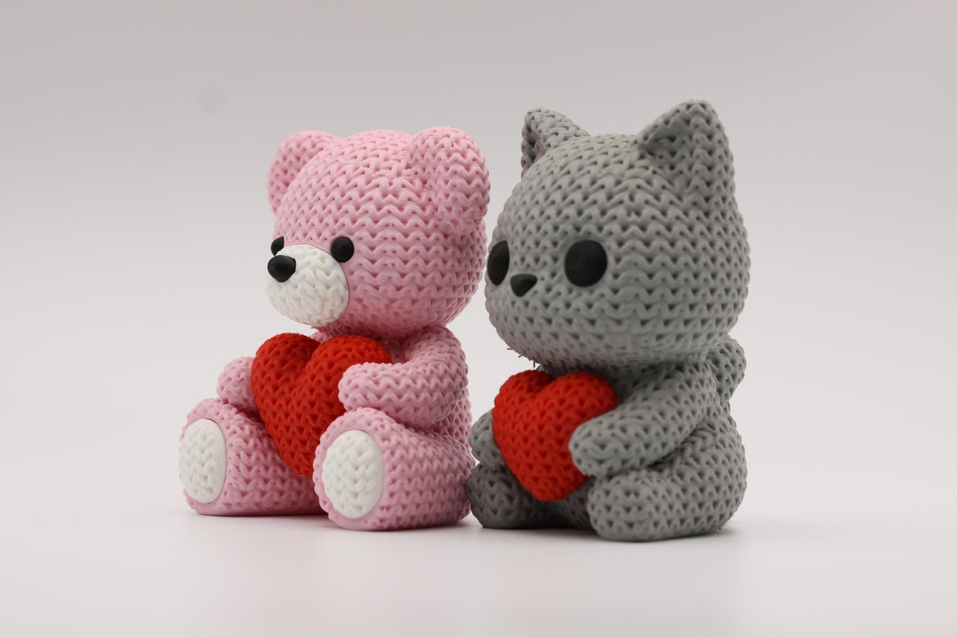 Teddybjørn og katt som holder et hjerte 3D-printet i strikket design