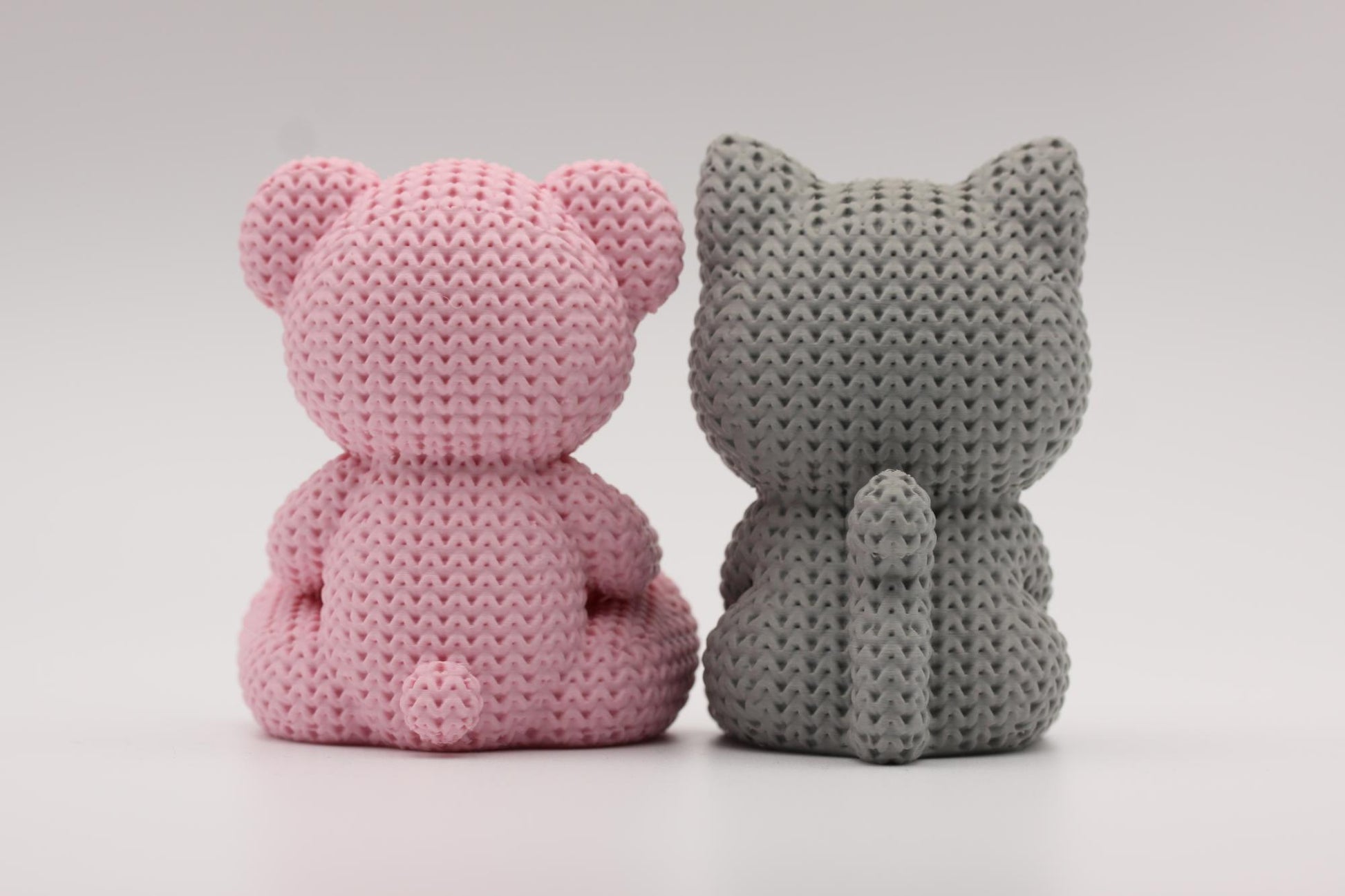 Teddybjørn og katt som holder et hjerte 3D-printet i strikket design