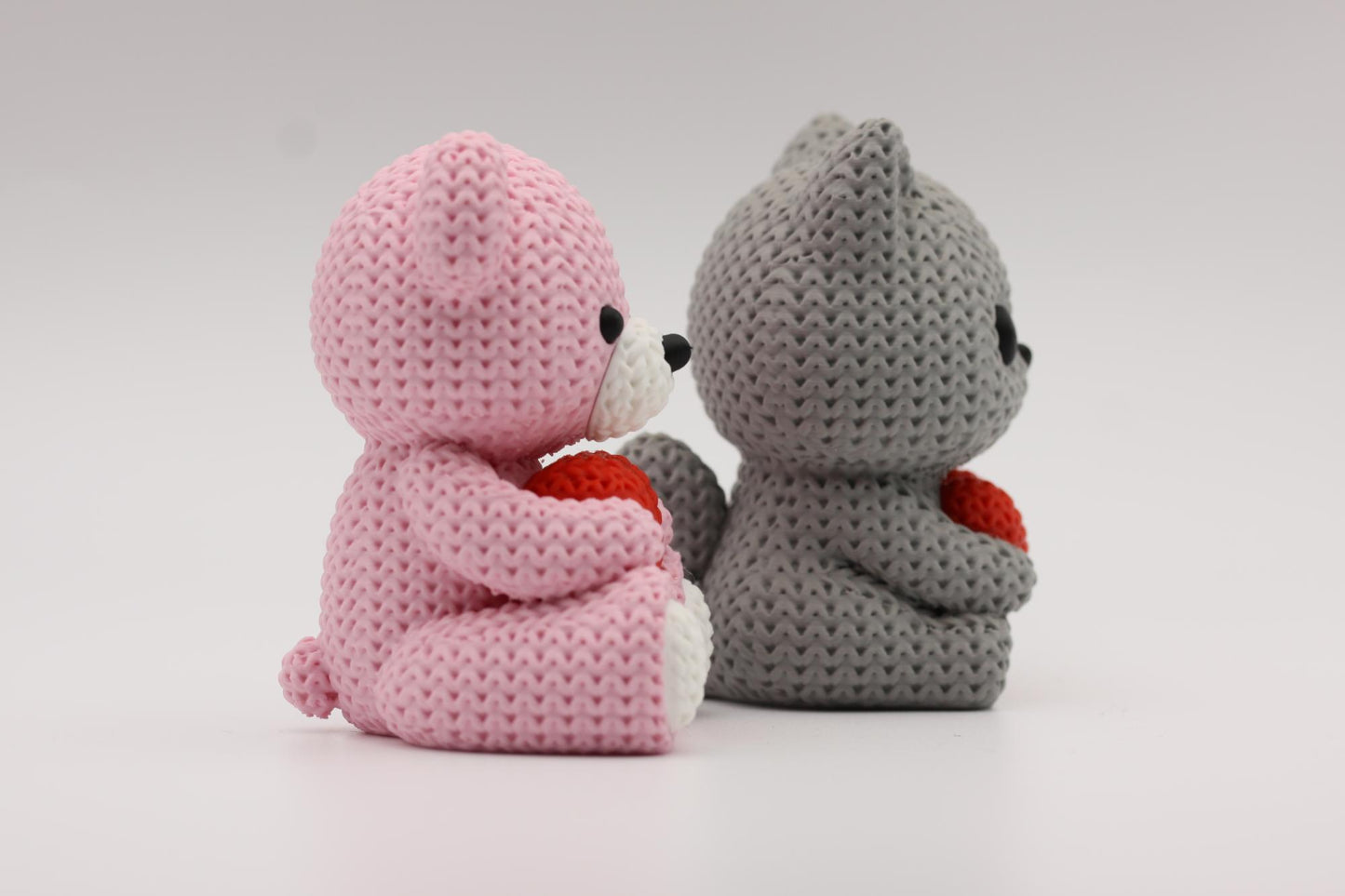 Teddybjørn og katt som holder et hjerte 3D-printet i strikket design