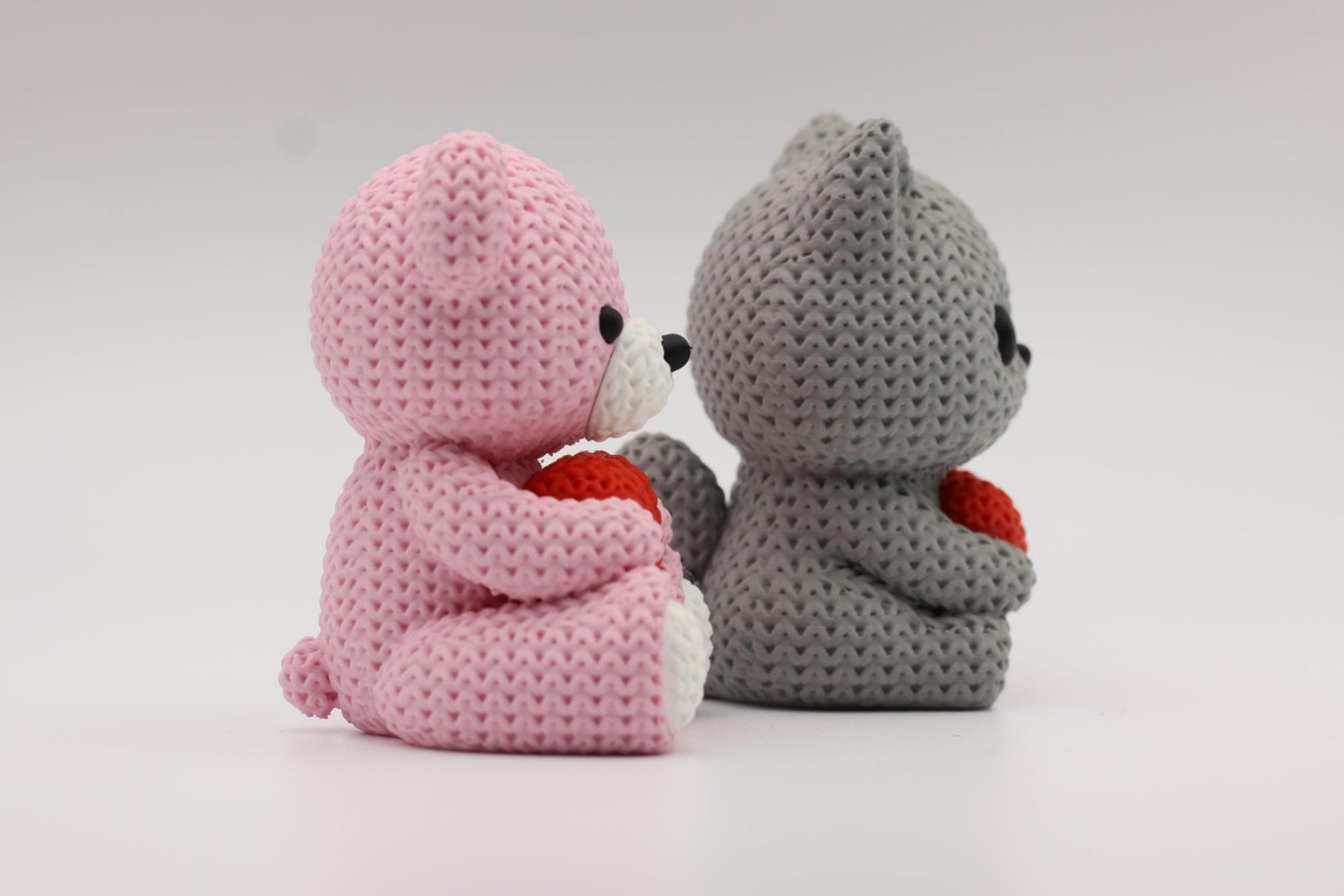 Teddybjørn og katt som holder et hjerte 3D-printet i strikket design